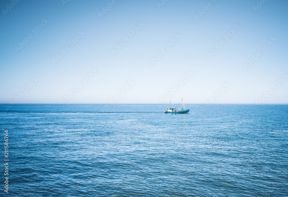 Obraz premium fishing vessel on wide blue ocean against clear sky