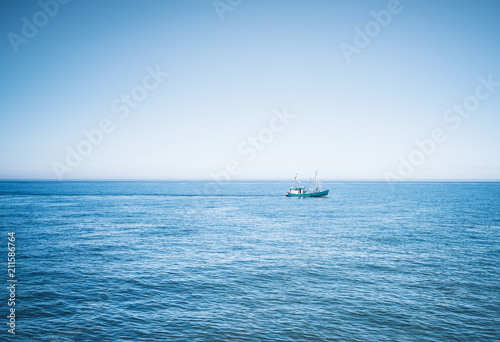 fishing vessel on wide blue ocean against clear sky