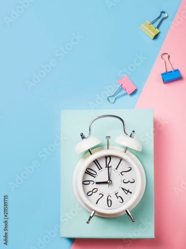 Alarm with supplies on color block background. Pastel minimalism