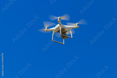 Drone with camera flying in blue sky