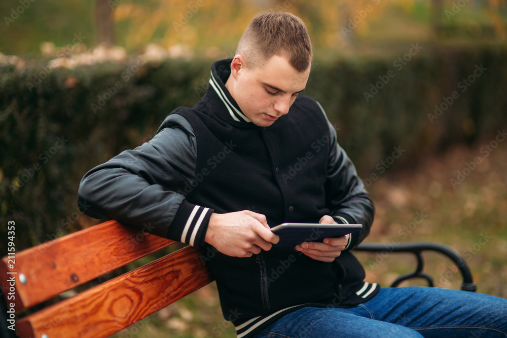 A young guy in a black jacket uses a tablet A young guy in a black jacket uses a tablet