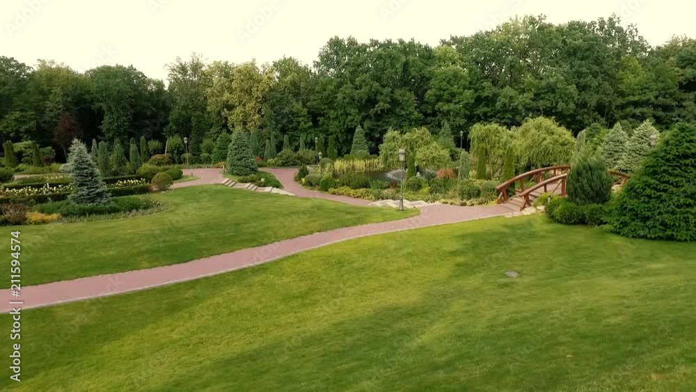 A public park with a shaved lawn and bushes and green trees on a sunny summer day. Beautiful formal garden A public park with a shaved lawn and bushes and green trees on a sunny summer day. Beautiful formal garden