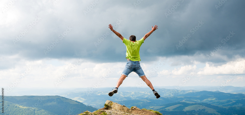 man jumping on the peak of the mountain