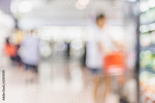 Blur background of customer shopping with shopping cart at Supermarket store product shelf with bokeh light.