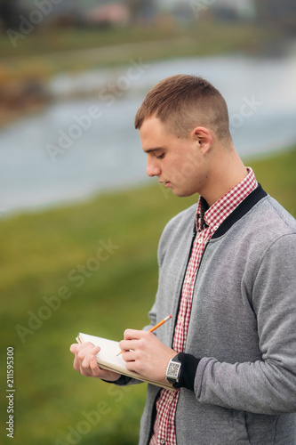 A cute student writes down his thoughts in his notebool using a pensil photo