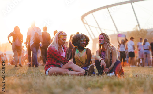 Young multiethnic girls sitting together at summer holi festival photo