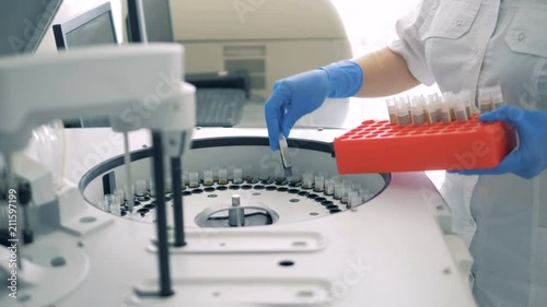 A laboratory worker loads a medical centrifuge to perform tests. 4K.