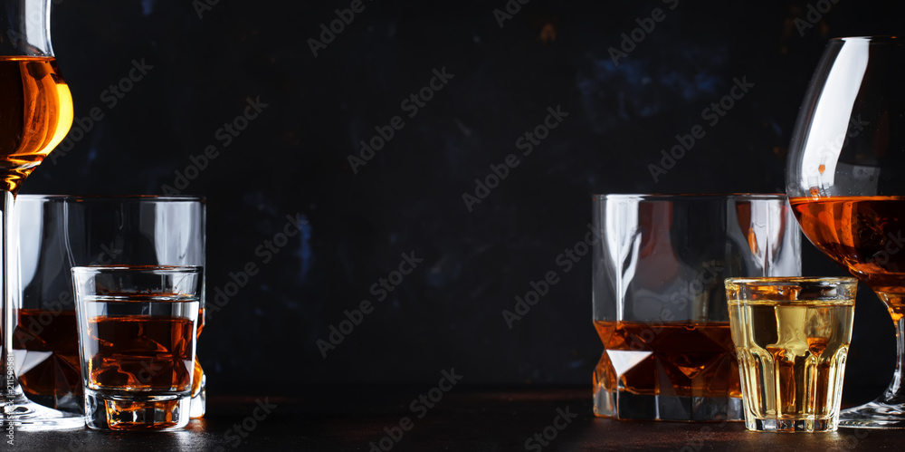Set of strong alcoholic drinks in glasses and shot glass in assortent: vodka, rum, cognac, tequila, brandy and whiskey. Dark vintage background, selective focus - obrazy, fototapety, plakaty 