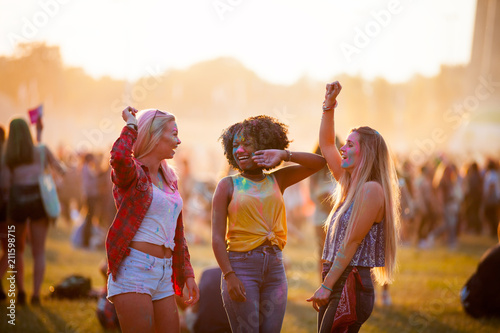 Multiethnic girls covered in colorful powder celebrating summer holi festival