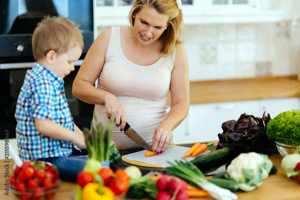Pregnant woman preparing meal with son Pregnant woman preparing meal with son