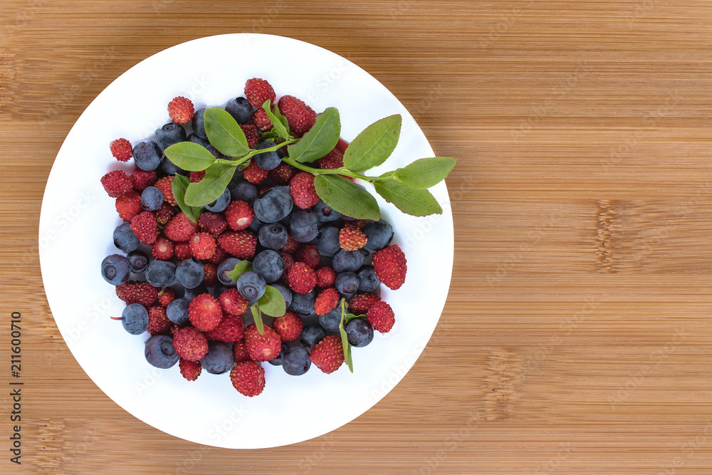 The forest berries. Strawberries and blueberries on a natural background. The forest berries. Strawberries and blueberries on a natural background.
