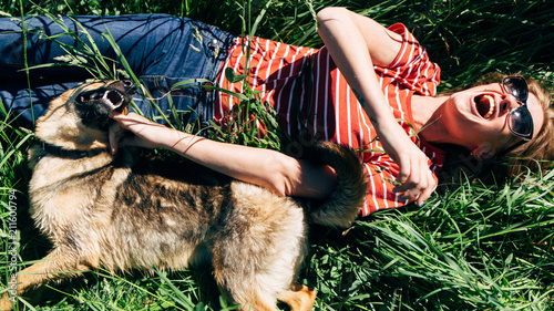 Photo of laughing woman with dog lying on lawn