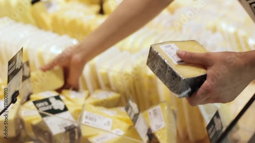 Hand of the buyer with a piece of cheese in the store