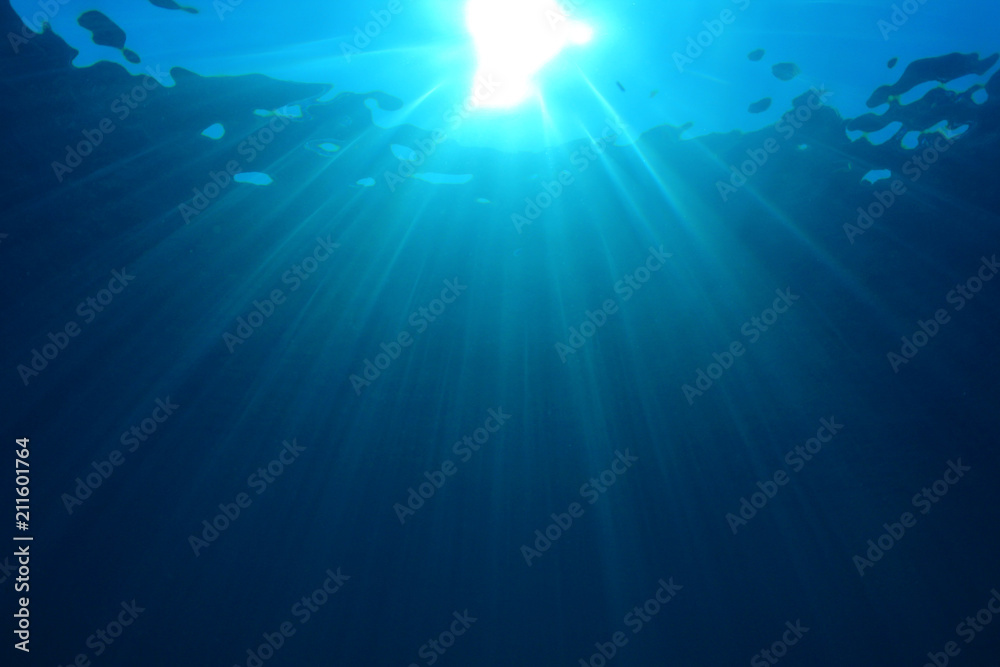 Underwater sunburst in blue sea 