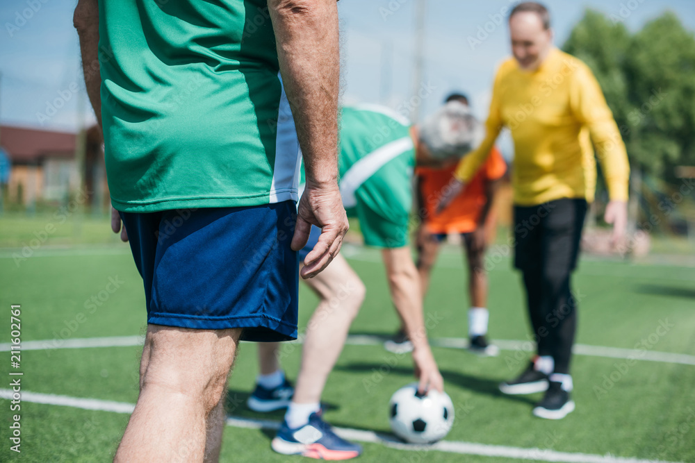 partial view of multicultural elderly friends playing football together partial view of multicultural elderly friends playing football together
