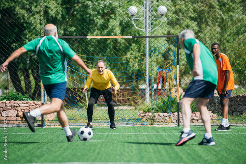 selective focus of multicultural elderly friends playing football together