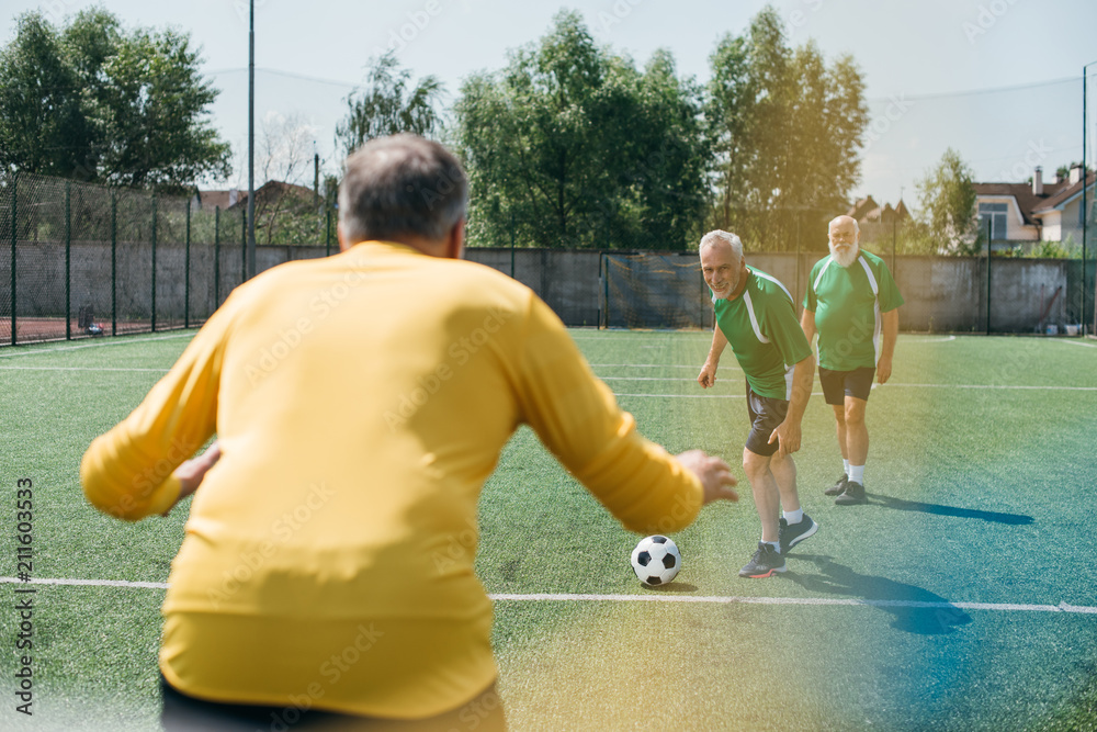 Obraz premium back view of goalkeeper and elderly men on football field