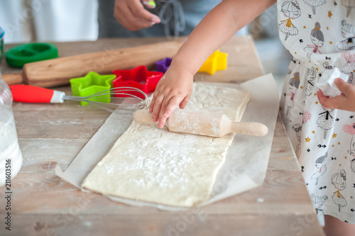 The process of baking from dough. Baby hands roll out the dough and make cookies in the form of asterisks on the dough