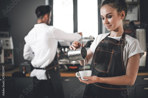 Professional barista woman pouring milk make coffee latte art at cafe