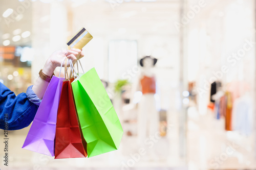 Woman with shopping bags with colourful and creditcard with cloth shop background - Shopping credit card payment concept
