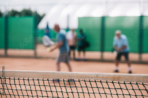 selective focus of net and tennis players playing tennis on court