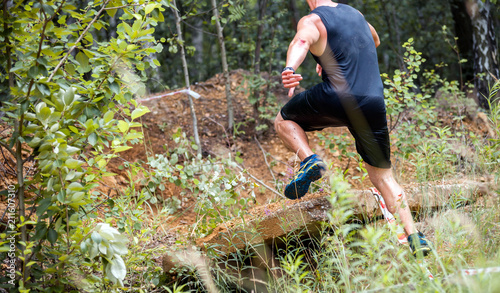 Trail running athlete jumping through rocks in the forest