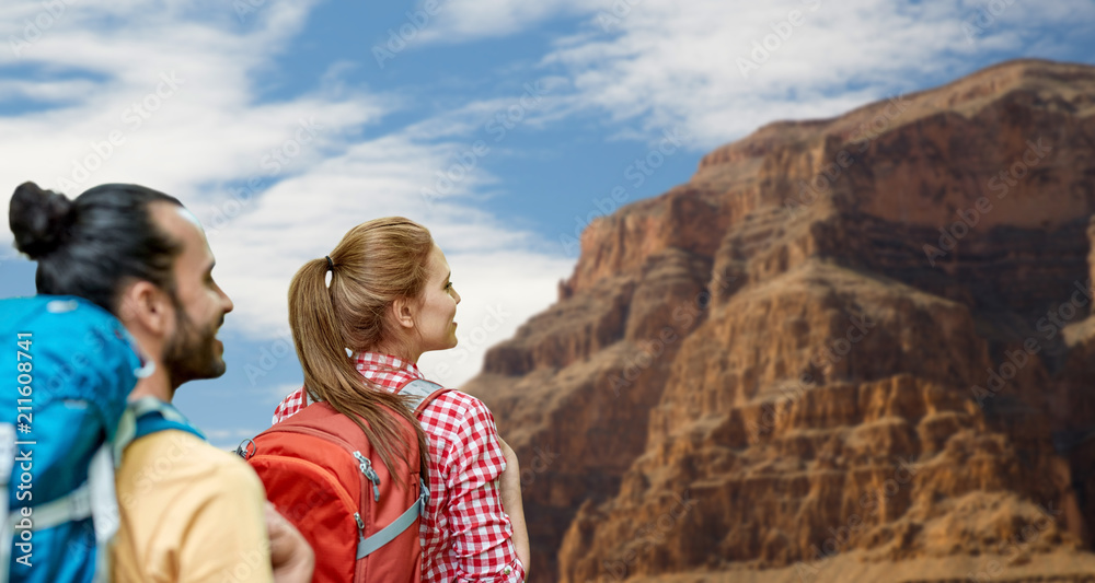 travel, tourism, hike and adventure concept - couple of travelers with backpacks over grand canyon national park background travel, tourism, hike and adventure concept - couple of travelers with backpacks over grand canyon national park background