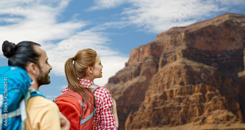 travel, tourism, hike and adventure concept - couple of travelers with backpacks over grand canyon national park background