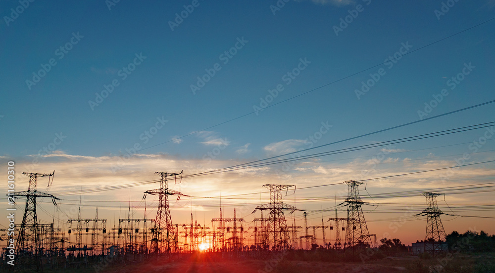 distribution electric substation with power lines and transformers, at sunset