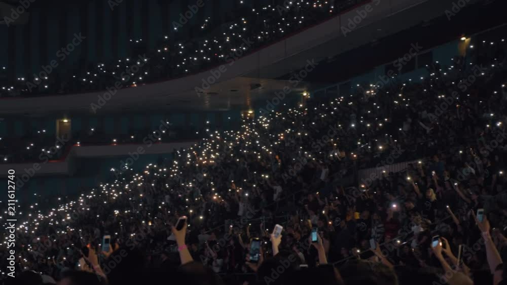 MOSCOW, RUSSIA - DECEMBER 16, 2013: Crowd of unidentified music fans waving mobile flashlights at the concert in Aquamarine theatre and music hall
