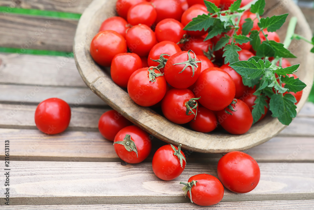 Fresh tomato crop in a wooden bowl Fresh tomato crop in a wooden bowl