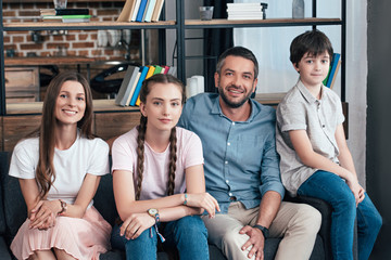 happy family with daughter and son sitting on sofa at home