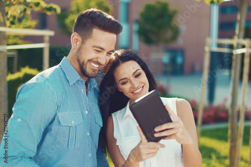 Happy young caucasian couple with tablet outdoors
