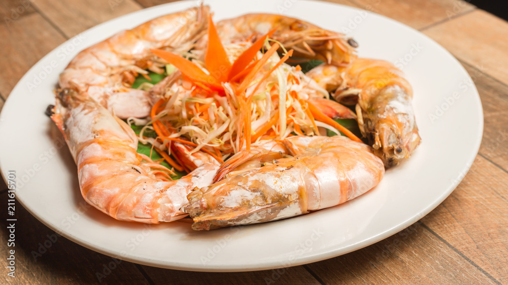 Steamed seafood or Steamed shrimp with herbs and vegetable in white dish on wood table. Steamed seafood or Steamed shrimp with herbs and vegetable in white dish on wood table.