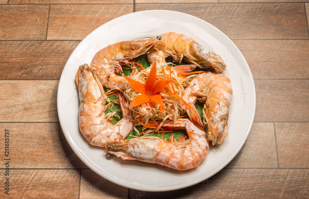 Steamed seafood or Steamed shrimp with herbs and vegetable in white dish on wood table. Steamed seafood or Steamed shrimp with herbs and vegetable in white dish on wood table.