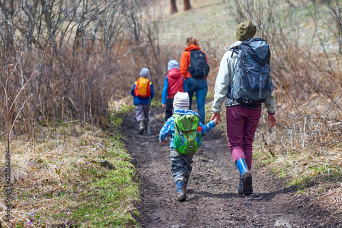 Hiking children with backpacks. Group boys, girls and adults go on a hike