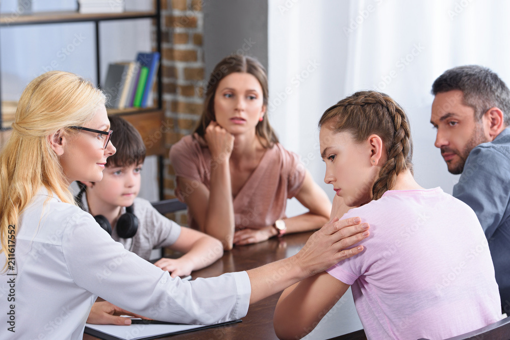 female counselor cheering up upset teenage girl on family therapy session in office female counselor cheering up upset teenage girl on family therapy session in office