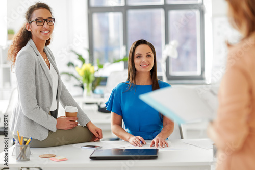 business and people concept - businesswomen listening to colleague at office presentation