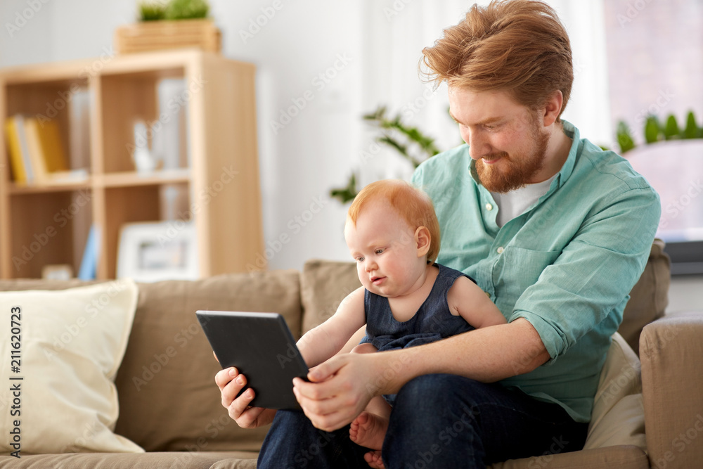 family, fatherhood and technology concept - happy red haired father and little baby daughter with tablet pc computer at home