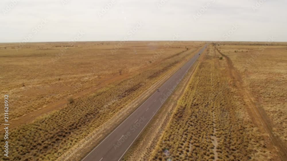 A wide shot of a green field and a long road in slow motion. Camera moves forward. A wide shot of a green field and a long road in slow motion. Camera moves forward.