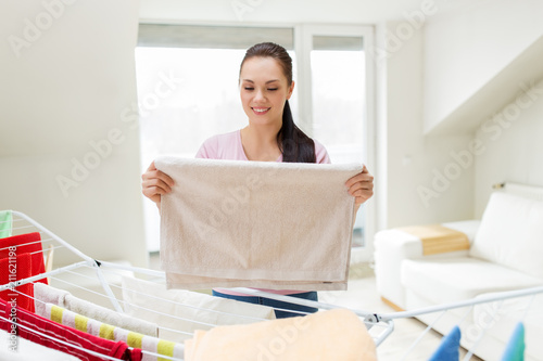 Billede på lærred laundry and household concept - happy woman or housewife taking bath towels from