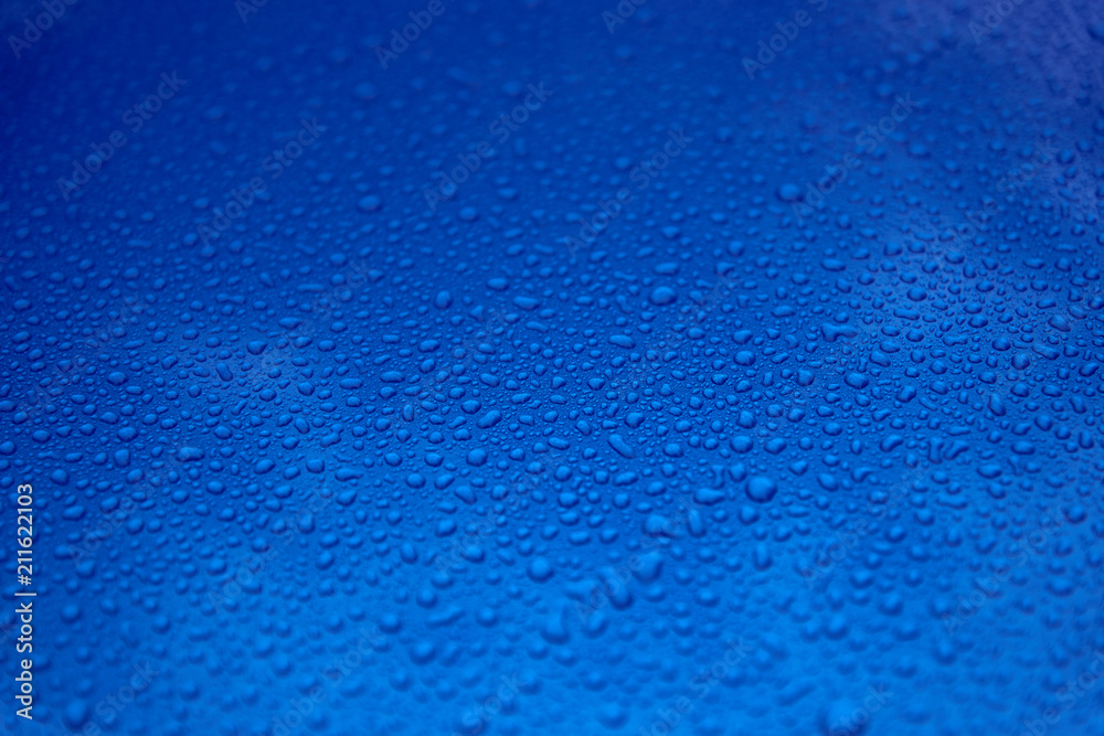 Obraz premium Rain drops on a blue smooth surface.