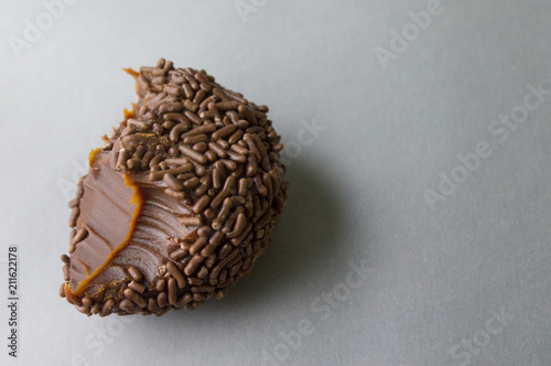 Grande doce brasileiro brigadeiro mordido isolado em fundo cinza