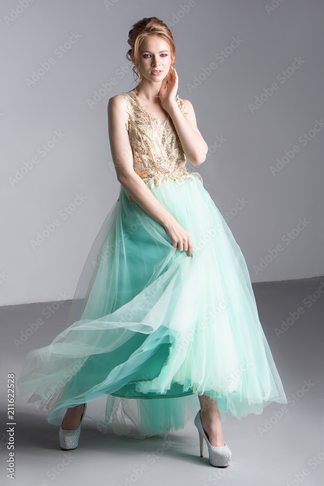 Fototapeta premium A beautiful fashion model in a long mint-colored dress and shiny shoes.