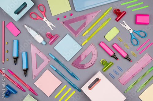 Neon multicolor stationery set as art pattern on grey background, flat lay.