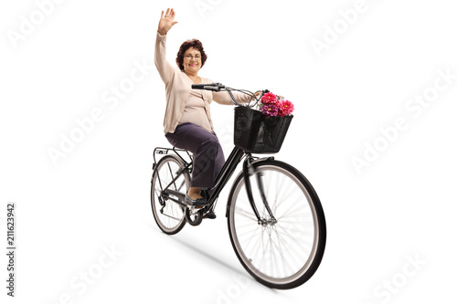 Mature woman riding a bicycle and waving at the camera