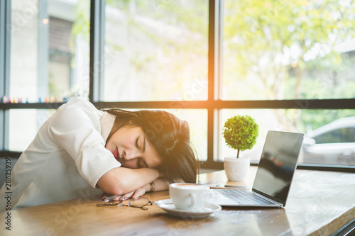 Foto Freelancer asian businesswoman tired after working coffee shop her sleeping on workplace table near windows at evening with digital laptop computer and coffe break