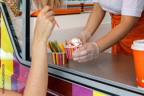 Seller's hands from the window stretches a wafer of soft cream ice cream. Street Trading