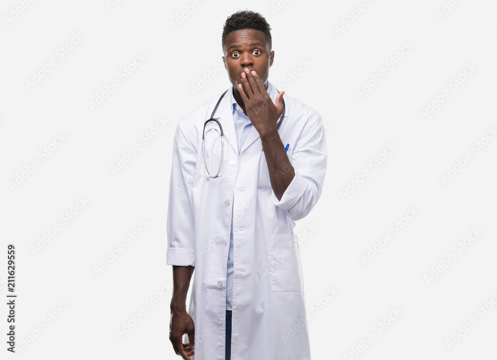 Young african american man wearing doctor coat cover mouth with hand shocked with shame for mistake, expression of fear, scared in silence, secret concept Young african american man wearing doctor coat cover mouth with hand shocked with shame for mistake, expression of fear, scared in silence, secret concept