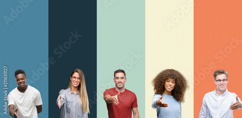 Group of people over vintage colors background smiling friendly offering handshake as greeting and welcoming. Successful business. photo